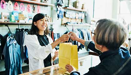 Business owner handing a customer her purchase.