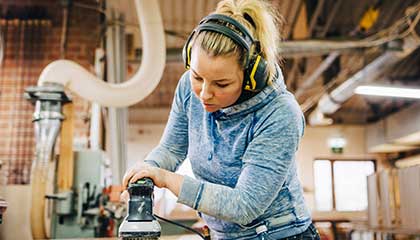 Woman working power-sanding wood